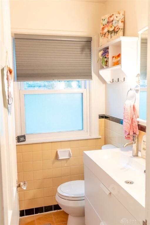 bathroom featuring tile patterned flooring, vanity, tile walls, and toilet