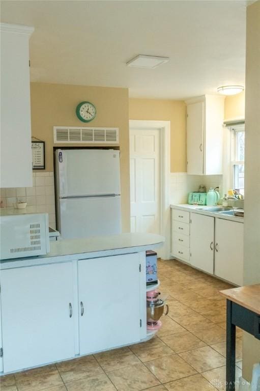 kitchen with white cabinetry, sink, tasteful backsplash, and white fridge