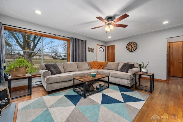 living room featuring ceiling fan, hardwood / wood-style floors, and a baseboard heating unit