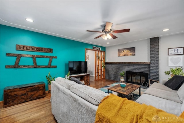 living room featuring ceiling fan, a fireplace, and light hardwood / wood-style flooring