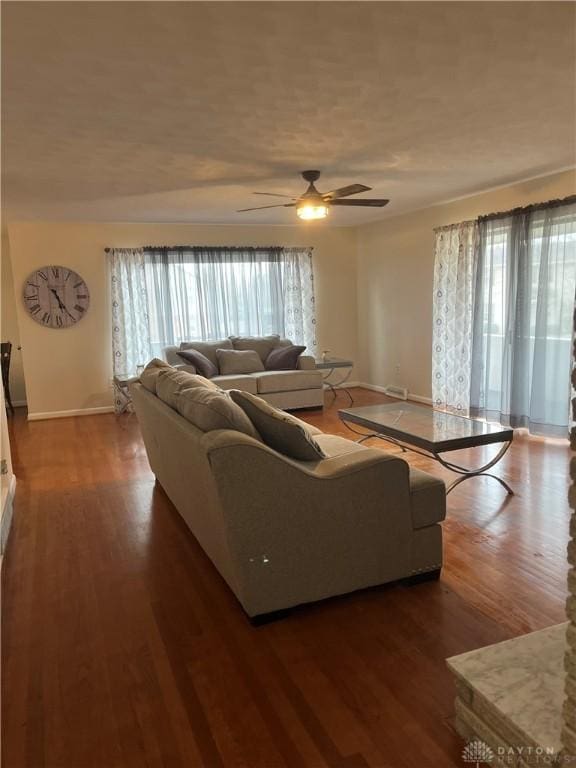 living room featuring dark wood-type flooring and ceiling fan