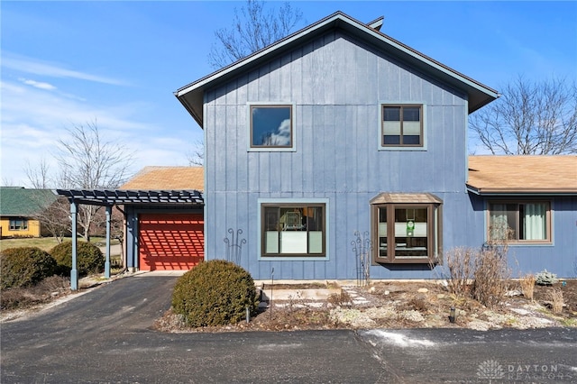 view of front of property featuring aphalt driveway, a pergola, and a garage