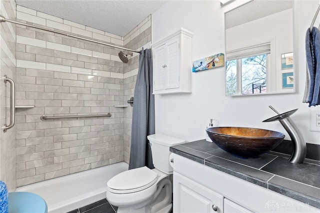 full bathroom featuring a shower stall, a textured ceiling, toilet, and vanity