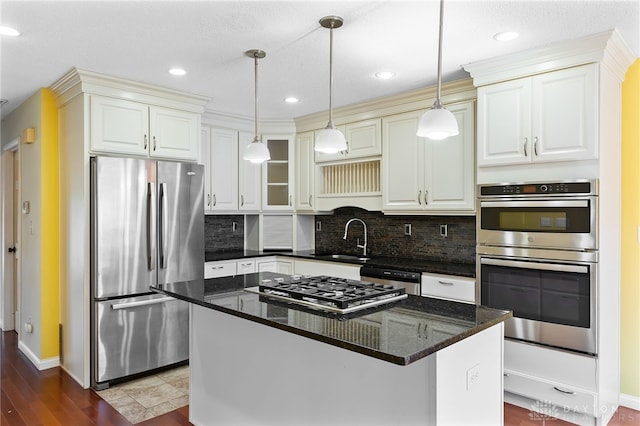 kitchen with a center island, decorative light fixtures, decorative backsplash, stainless steel appliances, and a sink