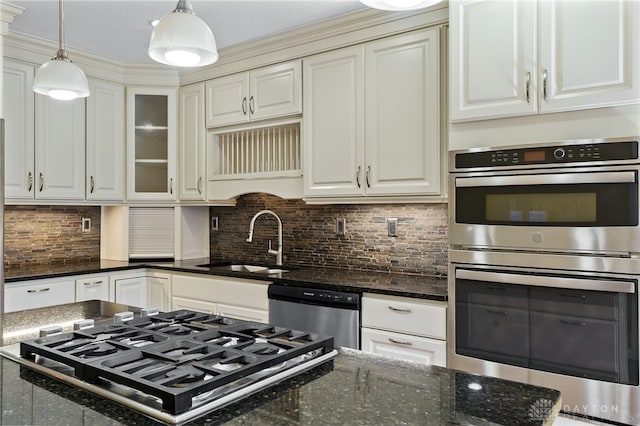 kitchen featuring a sink, stainless steel appliances, tasteful backsplash, and decorative light fixtures