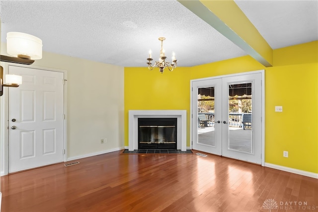 unfurnished living room featuring visible vents, beam ceiling, a fireplace with flush hearth, a textured ceiling, and wood finished floors