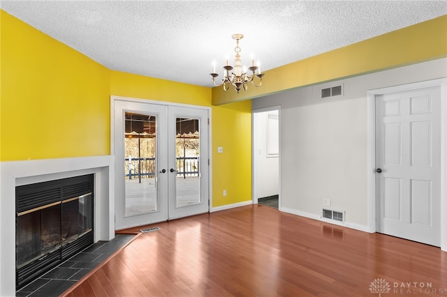 unfurnished living room with wood finished floors, visible vents, french doors, and a textured ceiling