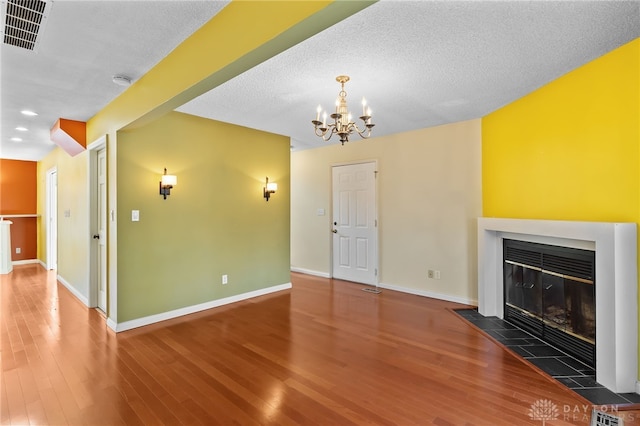 unfurnished living room featuring visible vents, baseboards, wood finished floors, and a tiled fireplace