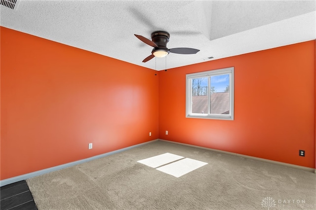 carpeted empty room with visible vents, baseboards, a textured ceiling, and ceiling fan