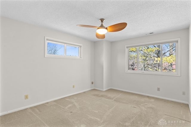 carpeted spare room with visible vents, baseboards, a textured ceiling, and ceiling fan