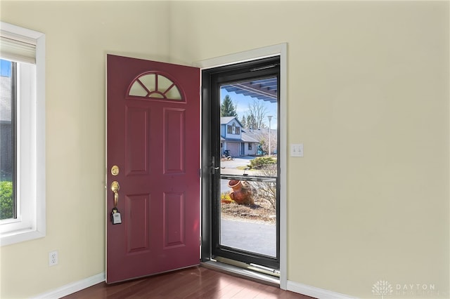 foyer featuring plenty of natural light, dark wood-style floors, and baseboards