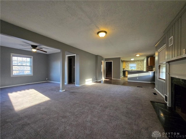 unfurnished living room with a textured ceiling, a fireplace, and dark carpet