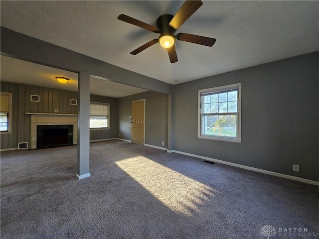 unfurnished living room featuring dark colored carpet, plenty of natural light, and a textured ceiling