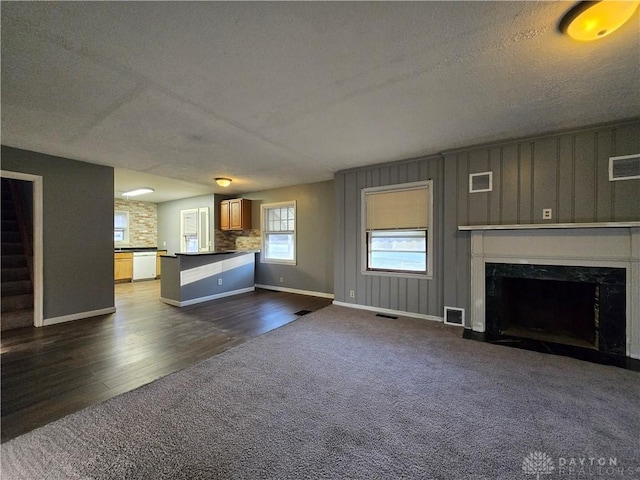 unfurnished living room with a premium fireplace, a textured ceiling, and dark carpet