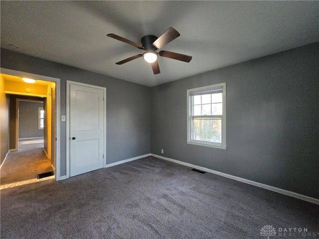 unfurnished bedroom with dark carpet and ceiling fan