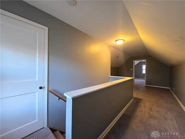 hallway featuring lofted ceiling and dark colored carpet