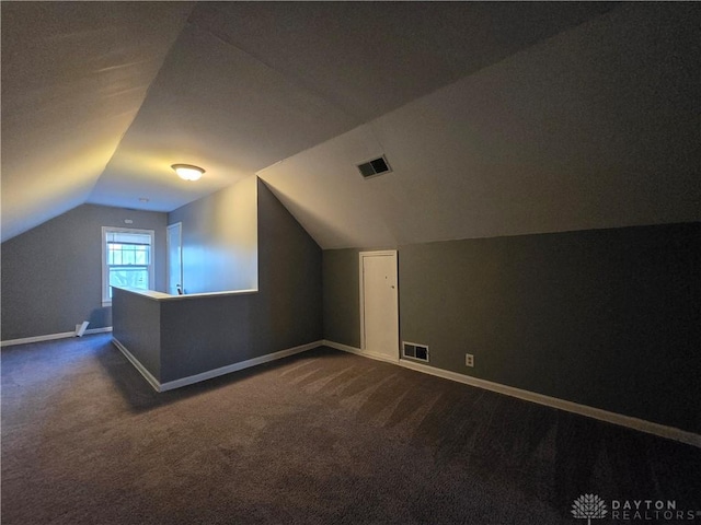 additional living space with vaulted ceiling and dark carpet