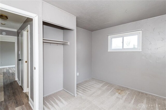 unfurnished bedroom featuring carpet floors, a textured ceiling, and a closet