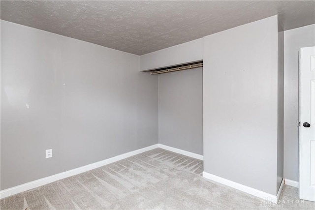 unfurnished room with a barn door, light colored carpet, and a textured ceiling