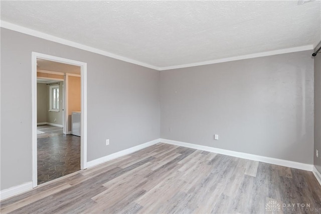 spare room featuring ornamental molding, light hardwood / wood-style floors, and a textured ceiling