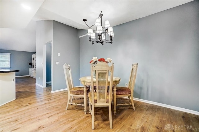 dining room featuring lofted ceiling, a notable chandelier, and light wood-type flooring