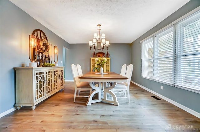 dining space featuring a chandelier, hardwood / wood-style floors, and a textured ceiling