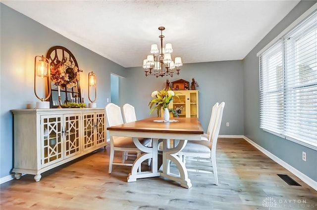 dining space with hardwood / wood-style floors and an inviting chandelier