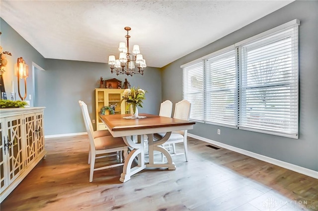 dining space featuring a notable chandelier and wood-type flooring