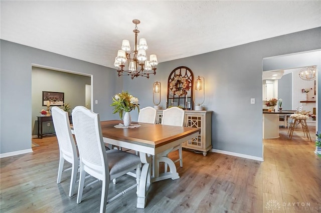 dining space with light wood-type flooring and a notable chandelier