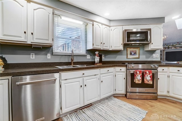 kitchen featuring stainless steel appliances, white cabinetry, sink, and light wood-type flooring