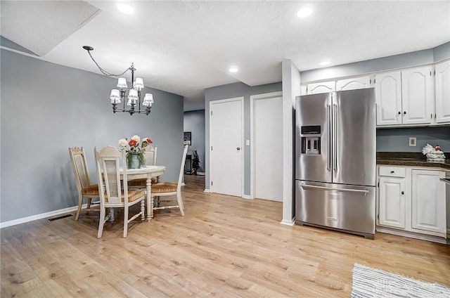 interior space featuring white cabinetry, high end fridge, an inviting chandelier, and light hardwood / wood-style flooring