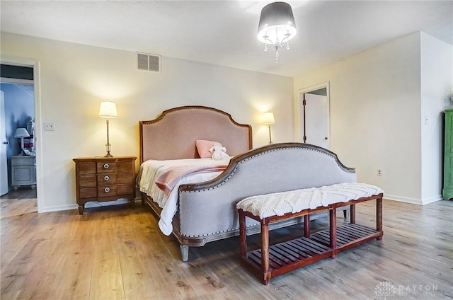 bedroom with light hardwood / wood-style floors and a notable chandelier