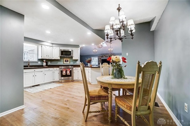 dining space with an inviting chandelier, sink, and light hardwood / wood-style floors