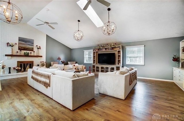 living room featuring wood-type flooring, high vaulted ceiling, ceiling fan with notable chandelier, and a fireplace