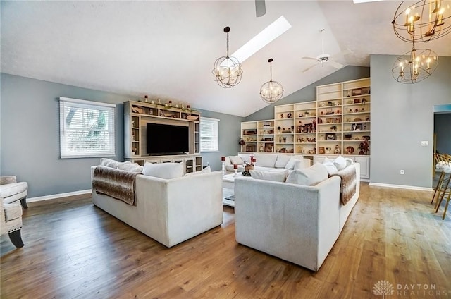 living room with hardwood / wood-style flooring, vaulted ceiling with skylight, and a chandelier