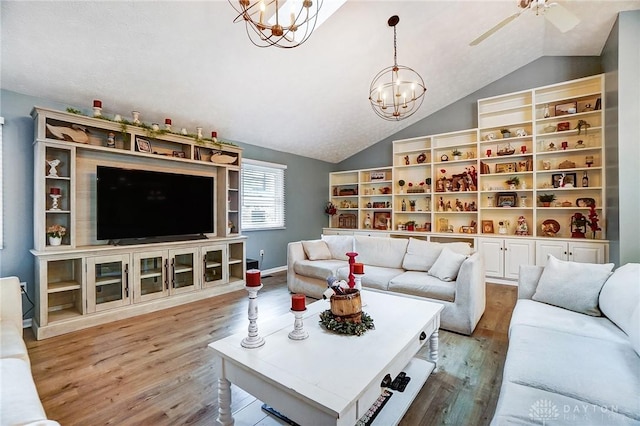 living room featuring lofted ceiling, ceiling fan with notable chandelier, and light wood-type flooring