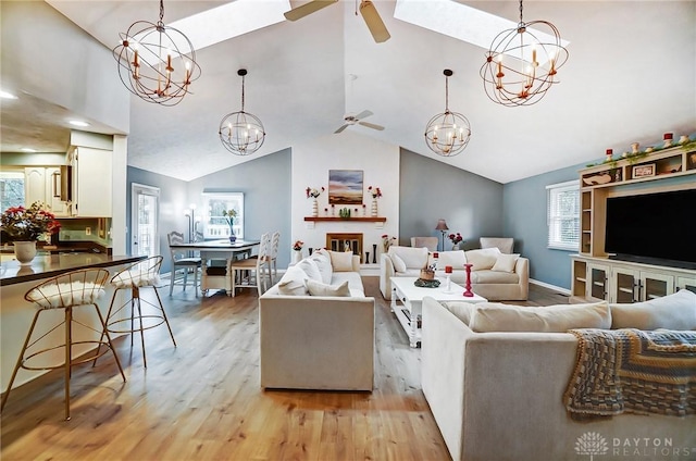 living room featuring high vaulted ceiling, ceiling fan with notable chandelier, and light hardwood / wood-style floors