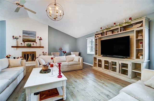 living room with lofted ceiling, a brick fireplace, light hardwood / wood-style floors, and ceiling fan