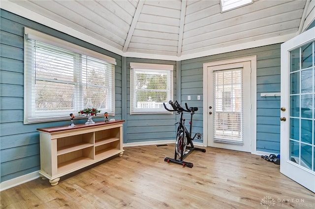 workout area featuring hardwood / wood-style flooring, lofted ceiling, and wooden walls