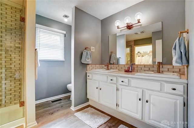 bathroom with hardwood / wood-style flooring, an enclosed shower, vanity, decorative backsplash, and toilet