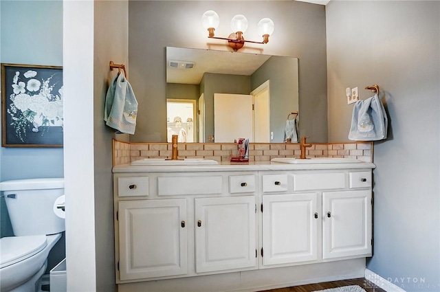 bathroom with tasteful backsplash, vanity, and toilet