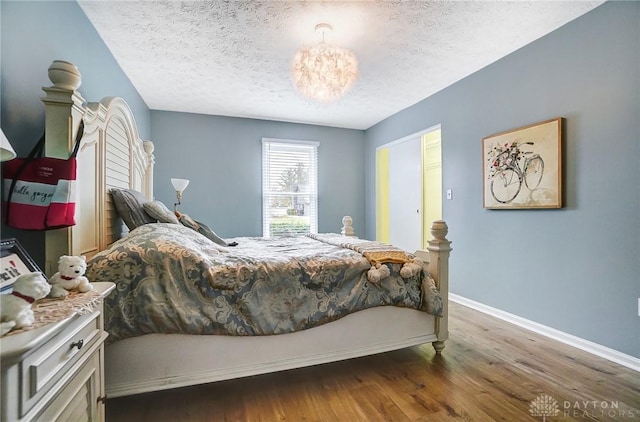 bedroom with hardwood / wood-style flooring, a notable chandelier, and a textured ceiling