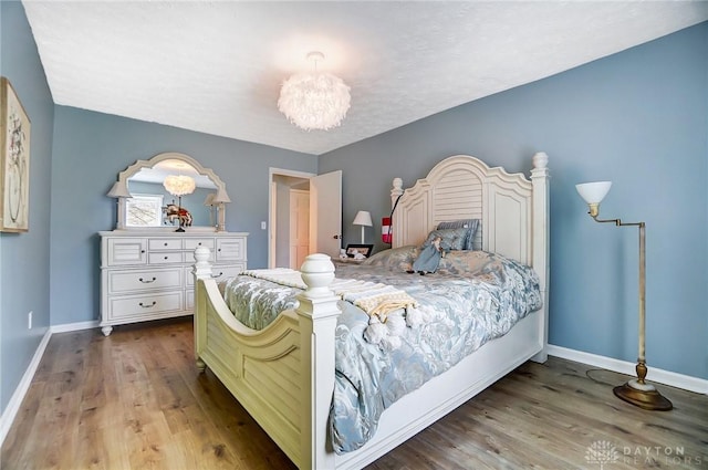 bedroom with hardwood / wood-style flooring and a notable chandelier