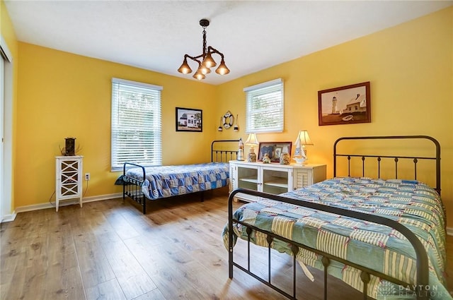 bedroom featuring a notable chandelier, multiple windows, and light hardwood / wood-style flooring