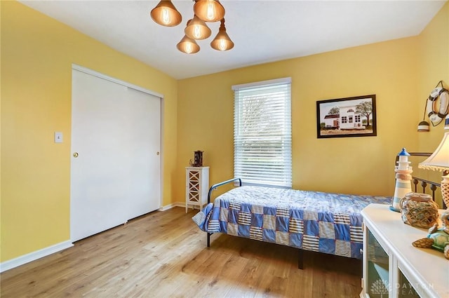 bedroom featuring an inviting chandelier and light hardwood / wood-style flooring