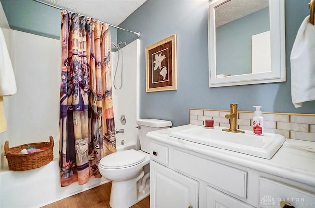 full bathroom with hardwood / wood-style flooring, vanity, shower / tub combo, toilet, and a textured ceiling