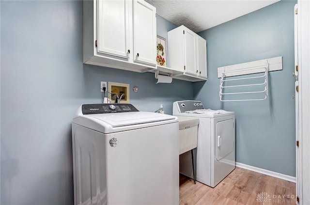 laundry area with cabinets, separate washer and dryer, and light wood-type flooring