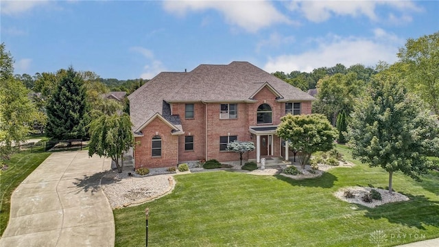 view of front of home featuring concrete driveway, brick siding, and a front lawn