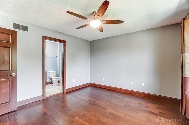 unfurnished bedroom with baseboards, visible vents, connected bathroom, wood finished floors, and a textured ceiling