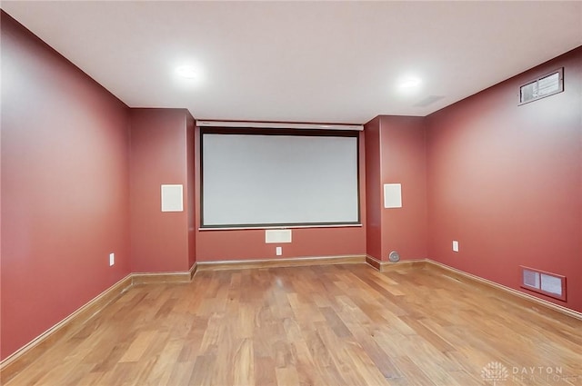 home theater room featuring light wood-style flooring, visible vents, and baseboards